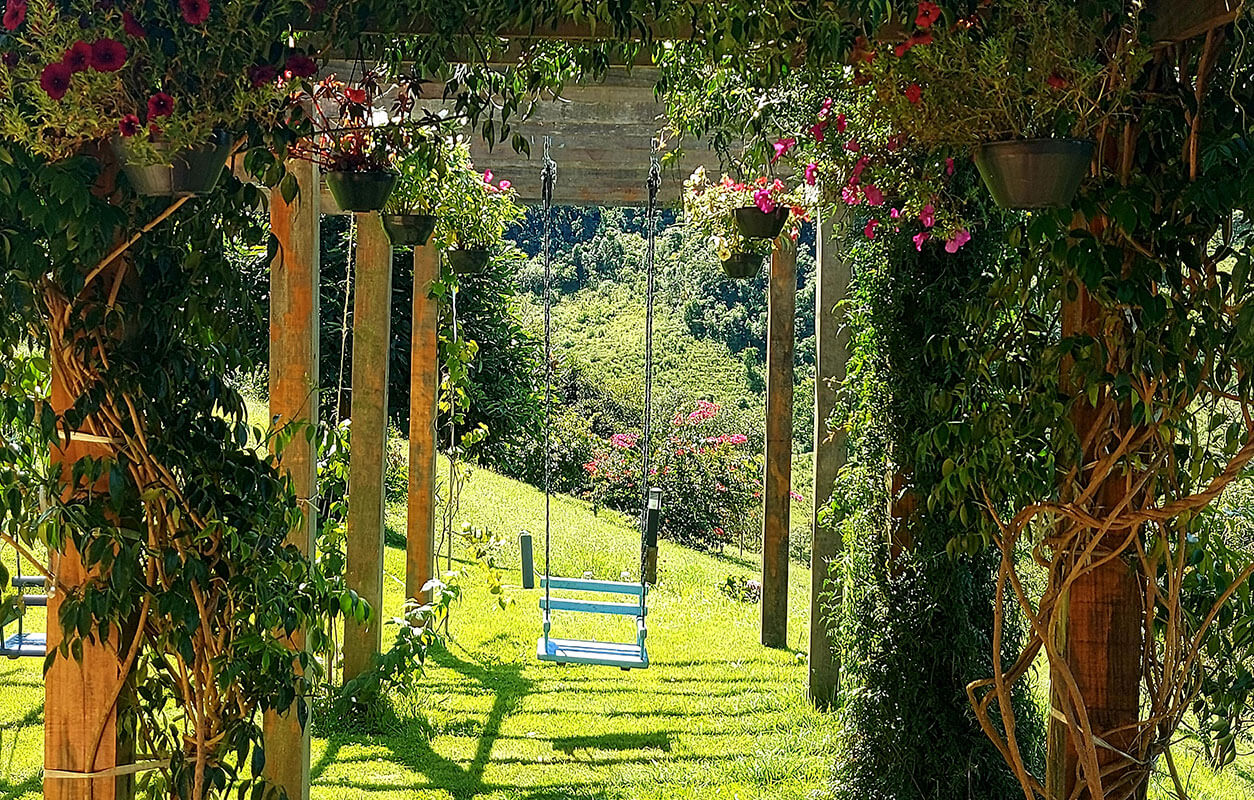 Arco de flores e balanço no jardim do Olival Alma da Mantiqueira, com vista para as montanhas